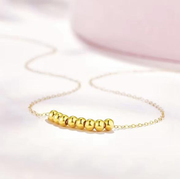 Gold beaded bracelet on a light pink background