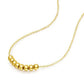 Gold necklace with three beads on a white background
