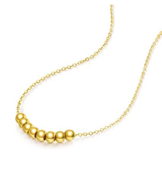Gold necklace with three beads on a white background