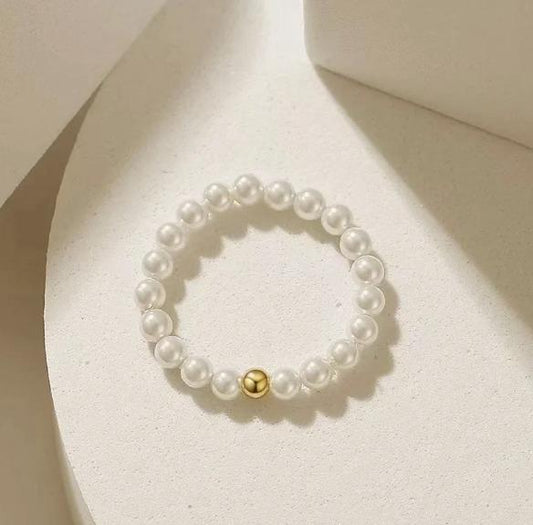 Pearl bracelet with a gold bead on a light beige background