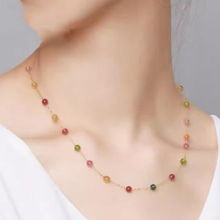 Necklace with multicolored beads worn by a person on a plain background