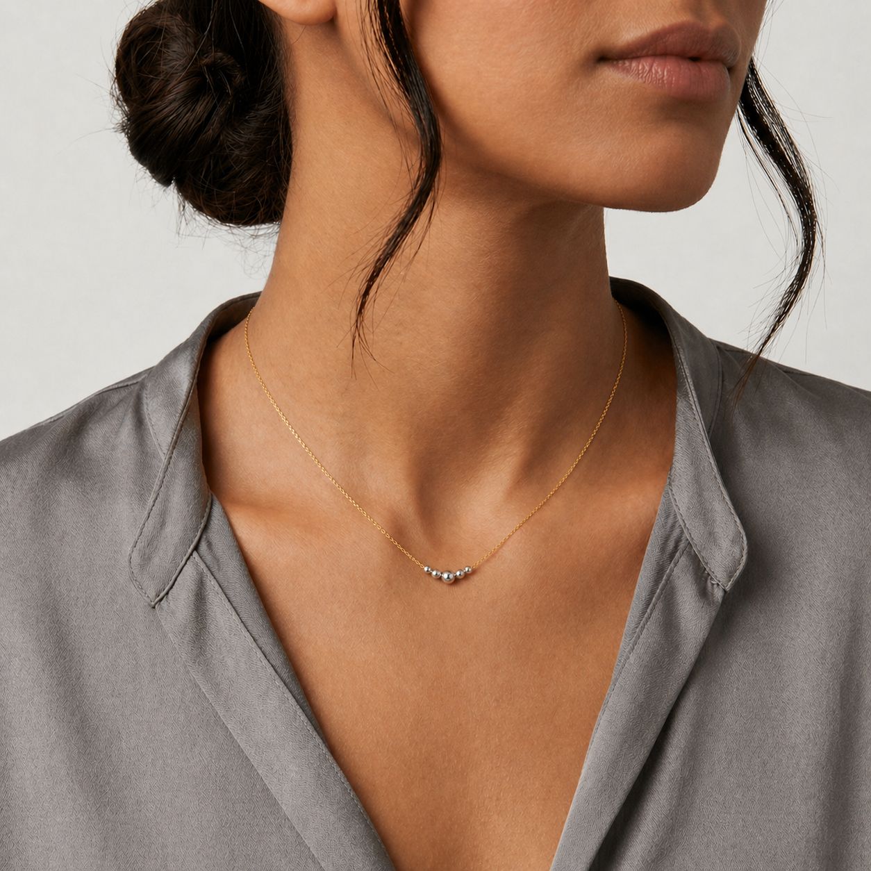Woman wearing a delicate gold necklace against a neutral background