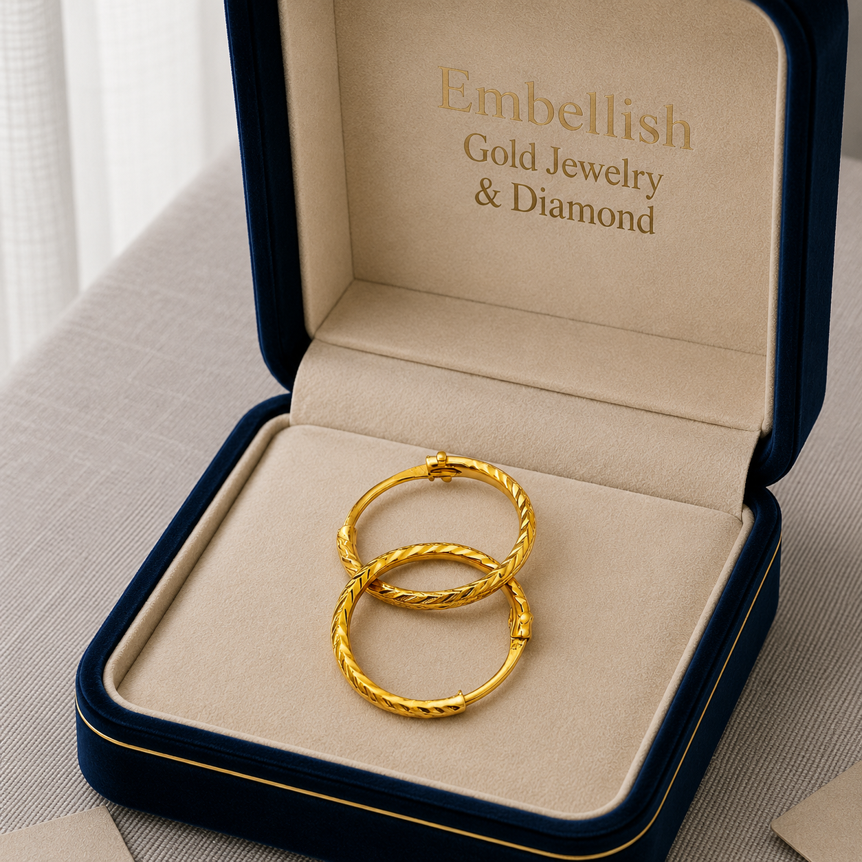 Gold hoop earrings in a 'Embellish Gold Jewelry & Diamond' box on a light background
