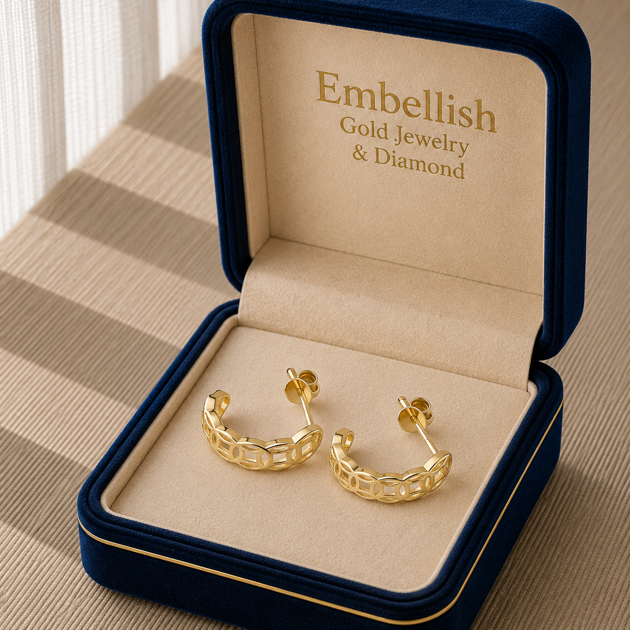 Gold hoop earrings in a 'Embellish Gold Jewelry & Diamond' box on a textured surface.