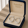Silver hoop earrings in an open jewelry box with 'Embellish Gold Jewelry & Diamond' branding.