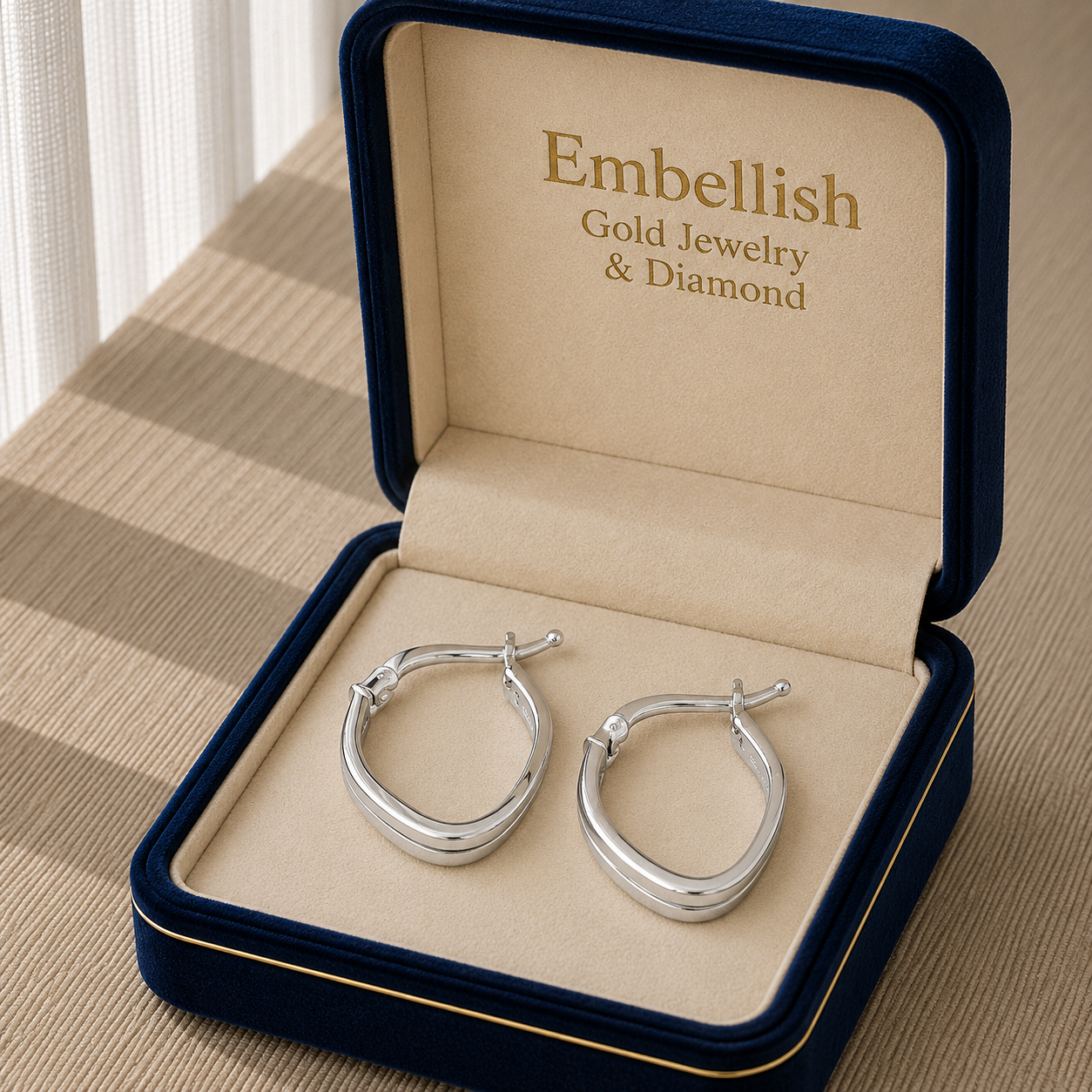 Silver hoop earrings in an open jewelry box with 'Embellish Gold Jewelry & Diamond' branding.