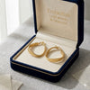 Gold hoop earrings in a 'Embellish Gold Jewelry & Diamond' box on a light gray surface.