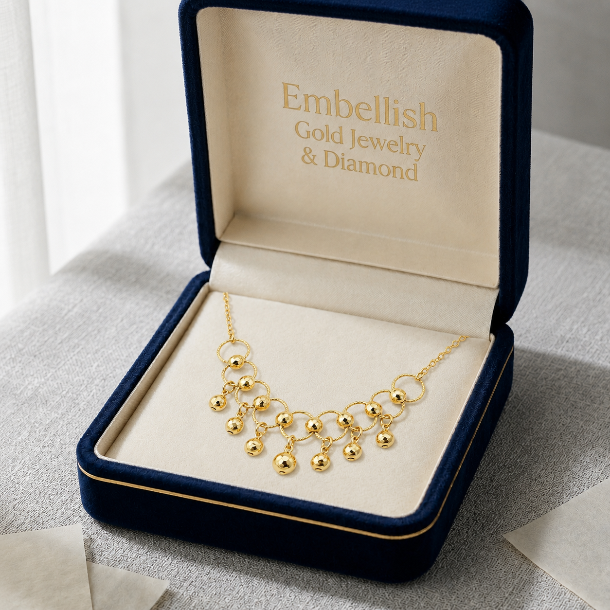 Gold necklace in an open jewelry box with 'Embellish Gold Jewelry & Diamond' branding.