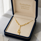 Gold necklace in a 'Embellish Gold Jewelry & Diamond' box on a textured surface