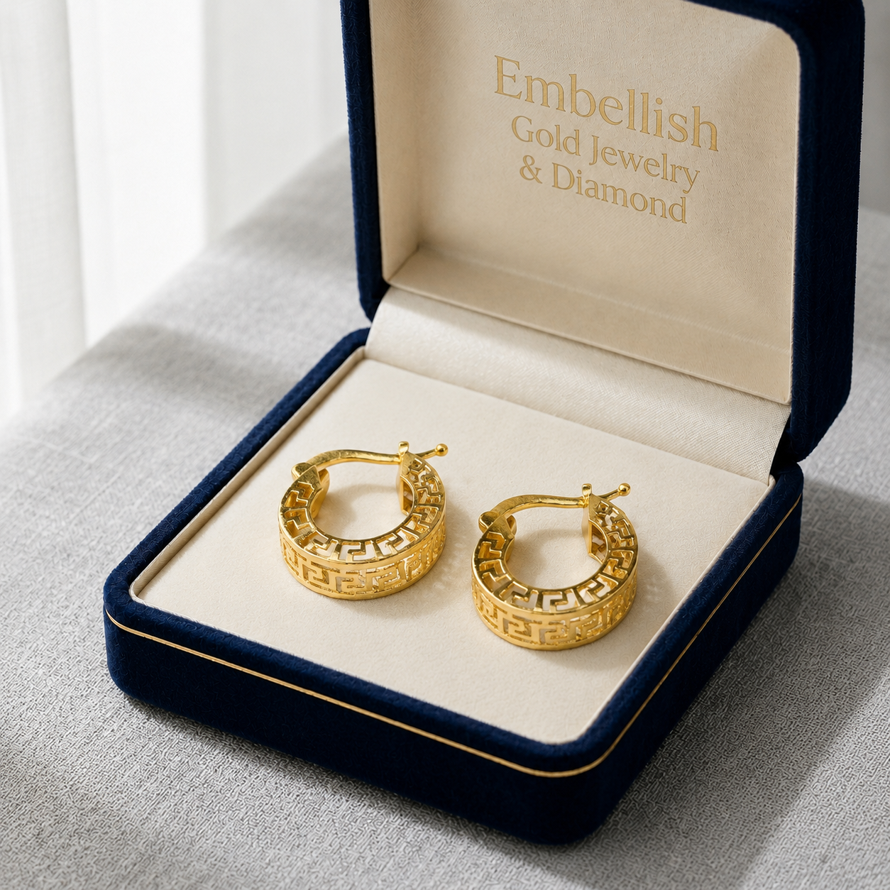 Gold hoop earrings in a 'Embellish Gold Jewelry & Diamond' box on a light gray surface.