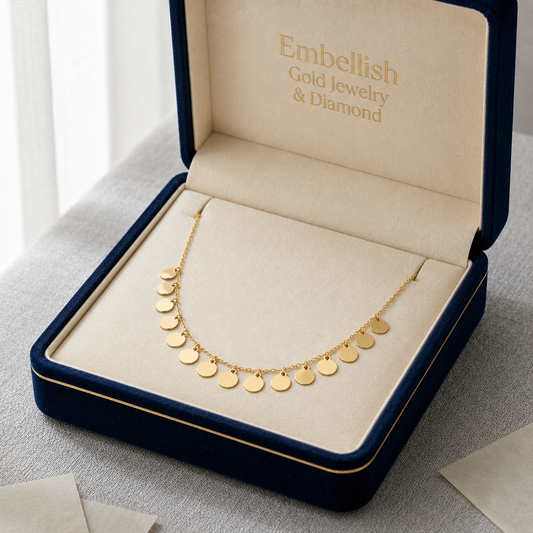 Gold necklace in an open jewelry box with 'Embellish' branding.