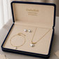 Gold jewelry set with heart-shaped charms in an 'Embellish' jewelry box.