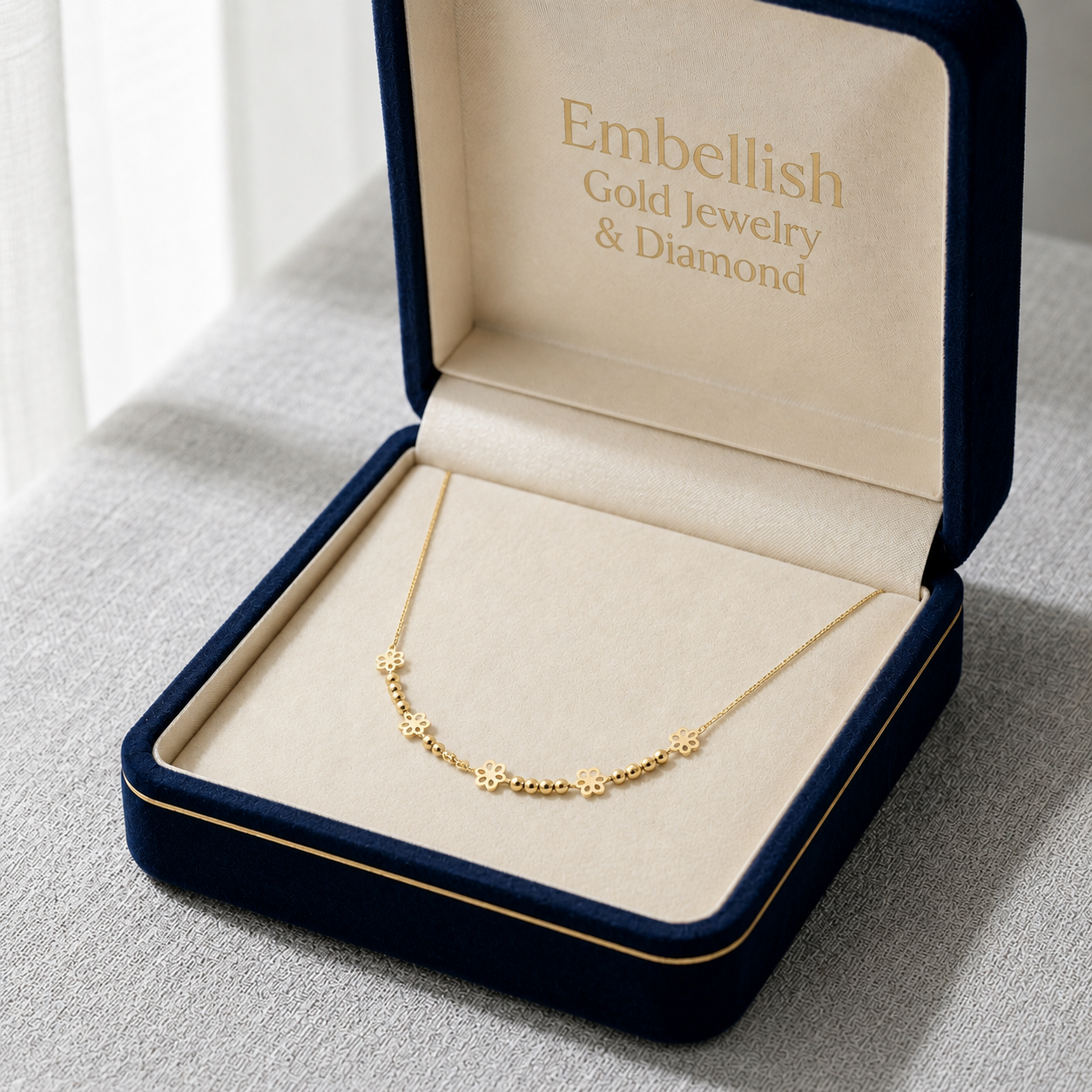 Gold necklace in an open jewelry box with 'Embellish Gold Jewelry & Diamond' branding.