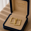 Gold hoop earrings in a 'Embellish Gold Jewelry & Diamond' box on a striped fabric background