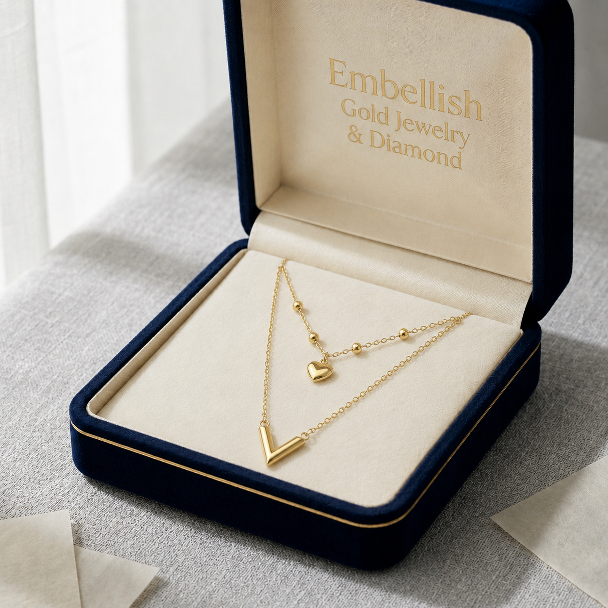 Gold necklace with heart and arrow pendants in an 'Embellish Gold Jewelry & Diamond' box.
