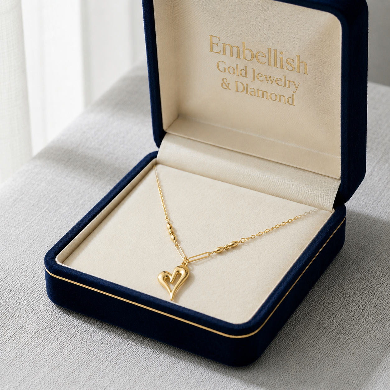 Gold necklace with a heart pendant in an 'Embellish Gold Jewelry & Diamond' box.