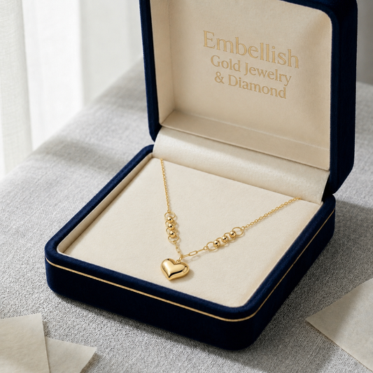 Gold necklace with a heart pendant in an open jewelry box labeled 'Embellish Gold Jewelry & Diamond'.
