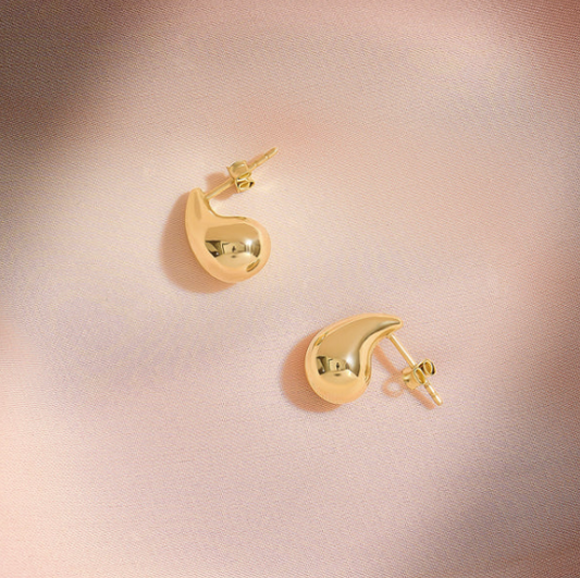 Gold earrings on a pink background